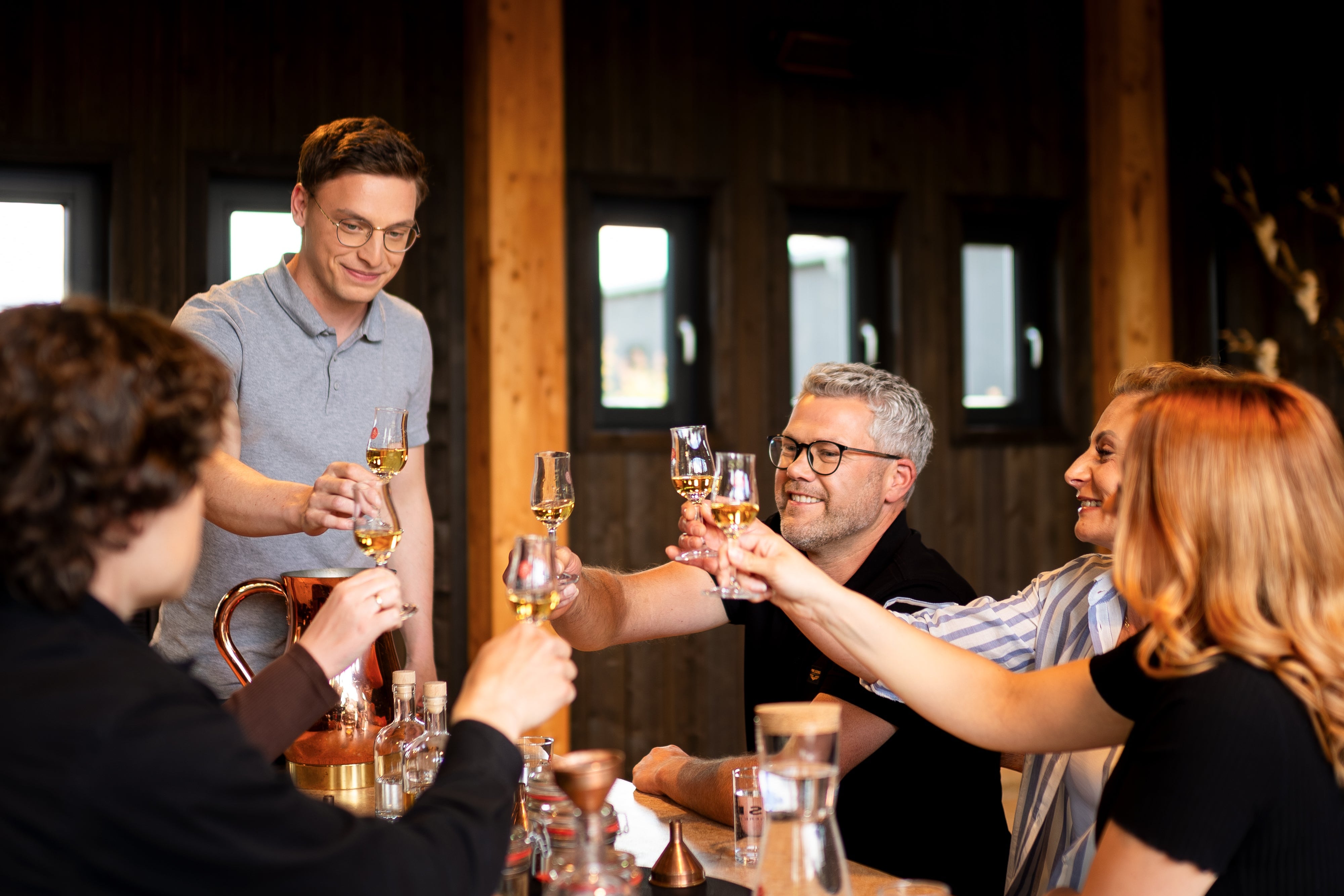 Menschen an einem Tisch beim Anstoßen mit Lagerkorn